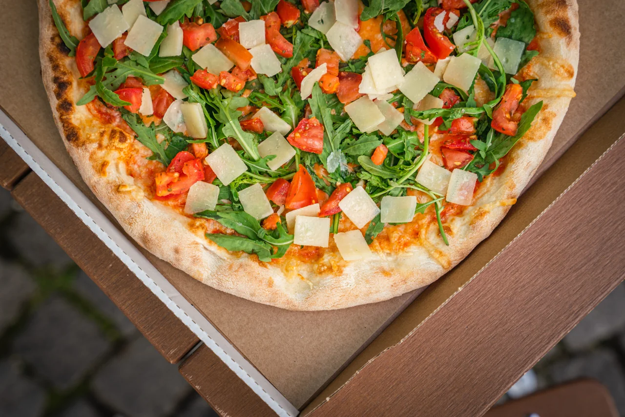 Pizza mit Rucola, Tomaten und Parmesansplittern
